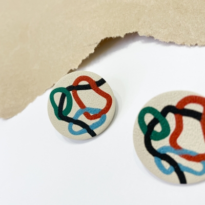 handmade circle polymer clay earrings with abstract colorfull lines and beige background 